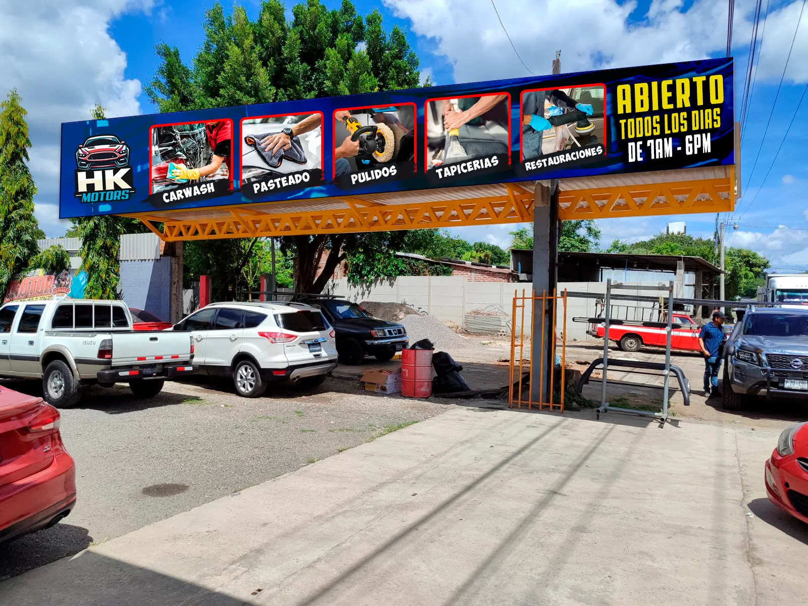 Rótulo de HK Motors sobre la isla trasera del taller con servicios de carwash, pulidos y tapicería